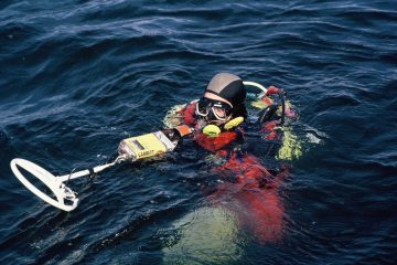 Man underwater with metal detector